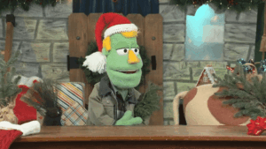 GIF of Kent Cook sketch Wreath Wreck showing half of a cow puppet backing into frame and bumping Kent Cook.